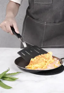 Close-up of black silicone fish spatula with stainless steel handle used in kitchen cooking.