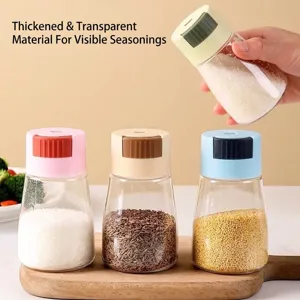 Set of 4 quantitative glass salt shakers with colorful lids on a wooden board.