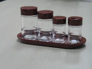 Set of four transparent acrylic seasoning bottles with brown lids and a matching display tray