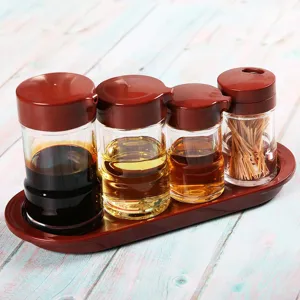 Detail view of transparent acrylic seasoning bottles with red lids on a matching tray