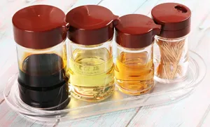Close-up of transparent acrylic oil and vinegar bottle set with brown lids on tray