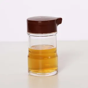 Close-up of a clear acrylic oil dispenser with a brown lid filled with yellowish oil