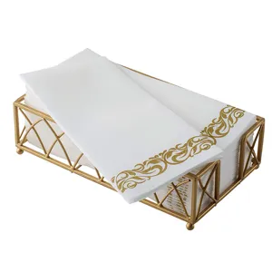 Detailansicht von weißen Einwegservietten mit goldenem Blumenmuster im Goldhalter.