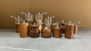 Detail view of manual wooden and glass pepper grinders, featuring durable acacia wood and metal.