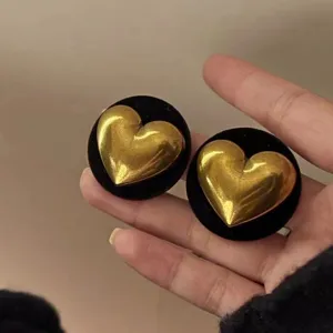 Detail of vintage gold heart stud earrings with black velvet circular backing