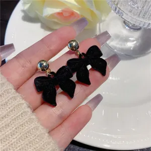 Detailed view of elegant black velvet flocking bow stud earrings with gold ball studs