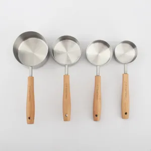 Detailed view of stainless steel measuring cups with beech wood handles and capacity markings