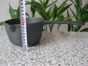 Detailed view showing the height measurement of a black cast iron mini milk pot with a tape measure