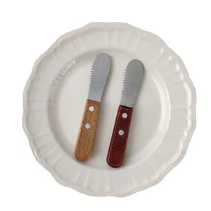Vintage Japanese style wooden handle stainless steel butter knives on a ceramic plate