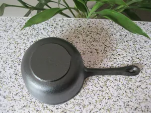 Detailed bottom view of a 16cm black uncoated cast iron mini milk pot with handle