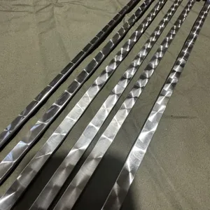 Macro detail view of premium textured stainless steel BBQ skewers with decorative patterns.