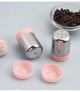 Vue détaillée de saupoudroire en acier inoxydable avec bouchon rose et poivre noir.