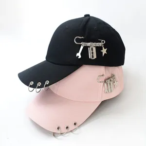 Close-up of punk style baseball caps with metal rings and safety pin charm details