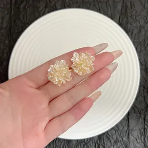 Detailansicht cremefarbener 3D-Blumen-Ohrstecker in der Hand mit zarten Blütenblättern