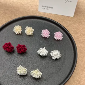 Detailansicht von fünf verschiedenen Paaren bunter 3D-Blumenohrstecker auf einem schwarzen Tablett