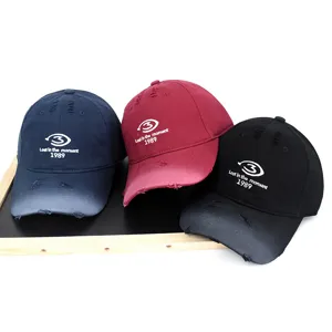 Collection of three distressed baseball caps in navy, burgundy and black featuring embroidery.