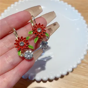 Detailed close-up view of red enamel sunflower earrings with sparkling rhinestone drop accents