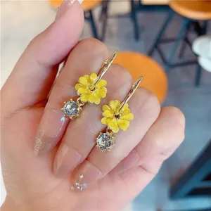 Detailed close-up of yellow sunflower earrings with sparkling clear zircon held in hand