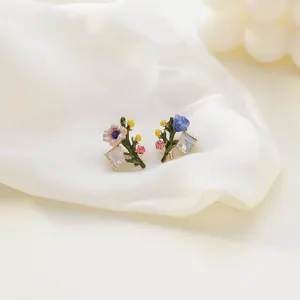 Macro view of forest-style floral stud earrings with sparkling crystals and enamel.