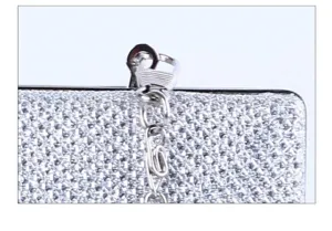 Close-up detail of silver glitter evening bag detachable metal chain and secure clasp design.
