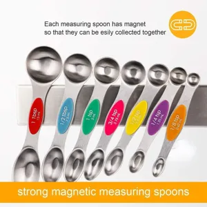 Primo piano di 7 misurini magnetici in acciaio inox con etichette di misura e doppie estremità