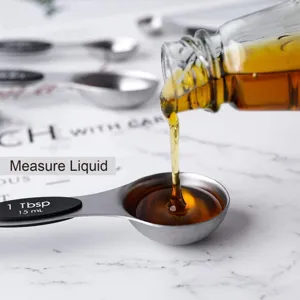 Dettaglio del cucchiaio misuratore in acciaio inox da 15 ml che versa del liquido