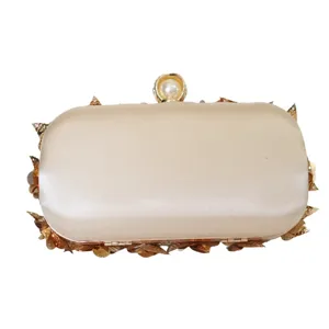 Elegant satin evening clutch bag with pearl clasp and gold leaf decoration for parties.