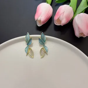 Dettaglio di eleganti orecchini a foglia con smalto blu e cristalli scintillanti