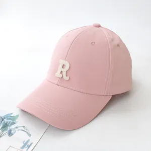 Detailed side view of a stylish pink baseball cap featuring a white embroidered letter R