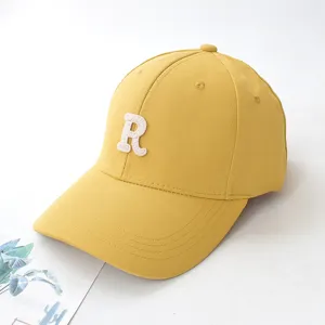 Detailed close-up view of a yellow baseball cap featuring a white embroidered letter R logo