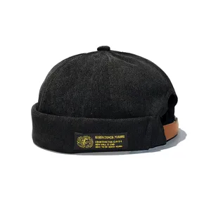 Macro view of black corduroy brimless miki hat with a vintage side woven label