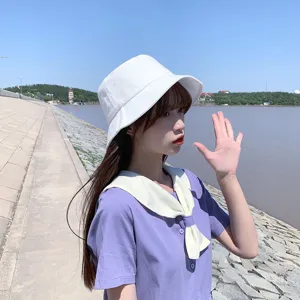 Detailed side view of a minimalist white cotton bucket hat for summer sun protection.