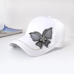 White baseball cap for women with rhinestone mesh butterfly and sparkly chain decoration.