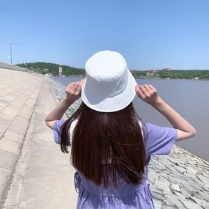 Back view of a woman wearing a white cotton bucket hat for sun protection outdoors.