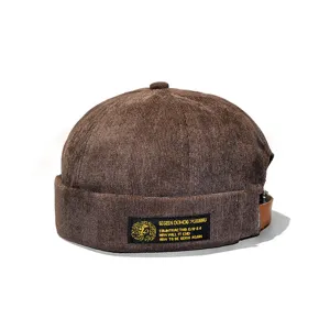 Detail view of brown corduroy brimless docker hat with a woven embroidered label