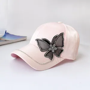 Pink baseball cap detail featuring a rhinestone black mesh butterfly and crystal brim chain.
