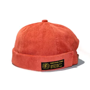 Detailed close-up view of a vintage orange corduroy brimless melon hat with label