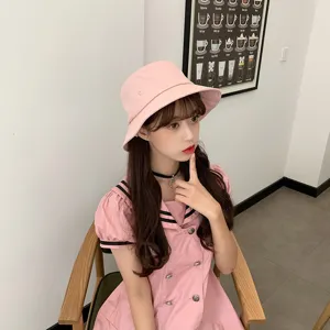 Model wearing a stylish pink bucket hat with matching pink dress in a minimalist setting