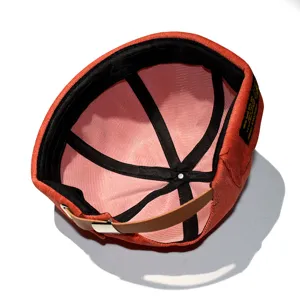 Stylish burnt orange corduroy skull cap featuring an adjustable brown leather strap back view