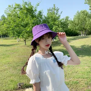 Lifestyle view of a young woman wearing a purple minimalist bucket hat in a park