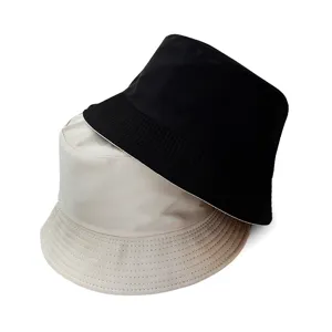 Close-up detail of double-sided bucket hats in black and beige, showing neat stitching.