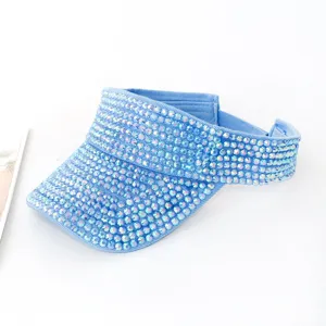 Dettaglio di una visiera in denim azzurro completamente ricoperta di strass iridescenti.