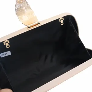 Élégant sac de soirée pochette beige avec fermoir feuille dorée et doublure noire.