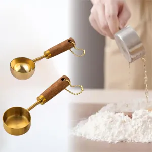 Close-up detail of gold-plated stainless steel measuring spoons with walnut handles