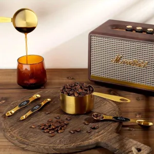Gold stainless steel measuring spoons and cups set detail shot with coffee beans and props.