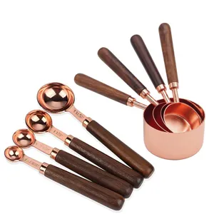 Set di 8 tazze e cucchiai misuratori con manici in legno e finitura in oro rosa per dolci.