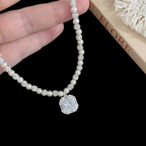 Dettaglio di una collana di perle di lusso con pendente a diamante quadrato lucido