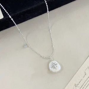 Macro detail of irregular cotton pearl necklace with silver starburst pendant motif