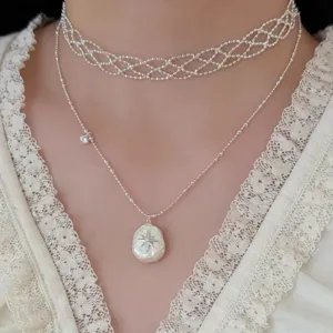 Close-up of irregular pearl starburst necklace with layered silver choker on model