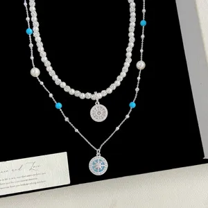 Gros plan d'un collier élégant à deux rangs avec pendentif boussole et perles